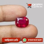 Close-up of a sparkling cushion-cut rich red natural African Ruby gemstone held between fingertips by Proyojonstore