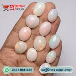 Multiple polished oval and round natural white Australian Fire Opal gemstones with vibrant rainbow fire displayed on an open hand by Proyojonstore