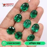 Array of eight sparkling faceted oval natural Russian Emerald gemstones displayed on an open hand by Proyojonstore