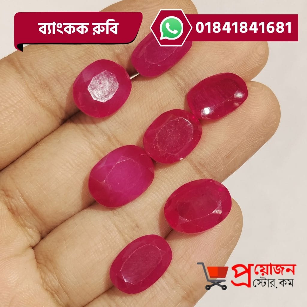 Multiple faceted oval pink-red natural Bangkok Ruby gemstones displayed across an open hand by Proyojonstore