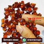 Macro view of a sparkling faceted oval honey-orange natural Srilankan Gomed gemstone held between fingertips above loose gems by Proyojonstore