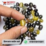 Close-up of a smooth honey-yellow natural Srilankan Cat's Eye gemstone showing a sharp vertical chatoyant line held between fingertips by Proyojonstore