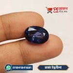 Dark violet-blue oval cut Marca Sapphire gemstone resting on finger - Proyojonstore