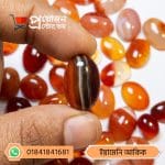 Macro view of a polished dark red and brown banded natural Yemeni Akik cabochon held between fingers by Proyojonstore