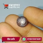 Macro view of a round polished greyish natural Star Ruby gemstone showing star asterism held between fingers by Proyojonstore