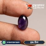 Oval dark violet Krishno Blue Sapphire gemstone held between two fingers