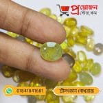 Macro view of a faceted oval lemon-yellow natural Ceylon Sapphire gemstone held between fingers by Proyojonstore