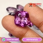 Close-up of a sparkling cushion-cut purple Alexander Alexandrite gemstone held between fingertips by Proyojonstore