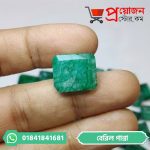 Macro close-up of a classic octagon step-cut green Beryl Emerald gemstone held between fingertips by Proyojonstore