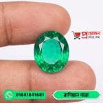 Macro view of a transparent oval faceted green Russian Emerald gemstone held between fingers by Proyojonstore
