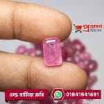 Close-up of a faceted rectangular octagon-cut pinkish-red Old Burma Ruby gemstone held between fingertips by Proyojonstore