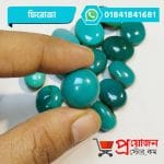 Fingertips holding a smooth polished round sea-green Feroza Turquoise gemstone above a pile of stones by Proyojonstore