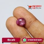 Close-up of an oval polished pinkish-purple natural Star Ruby gemstone held between fingertips by Proyojonstore