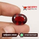Detailed macro view of a large faceted oval natural reddish-brown African Gomed gemstone held between fingers by Proyojonstore