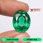 Detailed macro view of a sparkling high-clarity oval faceted natural Russian Emerald gemstone held between fingertips by Proyojonstore