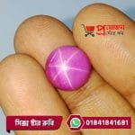 Macro view of a smooth round magenta-pink natural Star Ruby gemstone with prominent six-point star rays held between fingertips by Proyojonstore