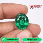 Close-up of a sparkling vivid green oval-cut Russian Emerald gemstone held between fingertips by Proyojonstore