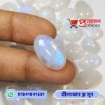 Close-up of a smooth polished oval natural Srilankan Blue Moonstone showing vivid blue flash held between fingertips by Proyojonstore