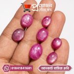 Multiple oval-shaped natural pinkish-red uncut Burmese Star Ruby gemstones displayed on an open hand by Proyojonstore