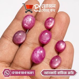Multiple oval-shaped natural pinkish-red uncut Burmese Star Ruby gemstones displayed on an open hand by Proyojonstore