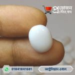 Close-up of a smooth oval polished milky white natural Australian Opal gemstone held between fingertips by Proyojonstore