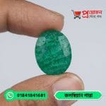Macro view of a faceted oval vivid green natural Colombian Emerald gemstone showing fine jardin inclusions held in hand by Proyojonstore