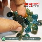 Hand holding a polished deep green rectangular Pitta Akik stone over a lot of green gemstones by Proyojonstore