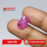 Macro view of a brilliant faceted oval pinkish-magenta natural Marka Ruby gemstone held between fingertips by Proyojonstore